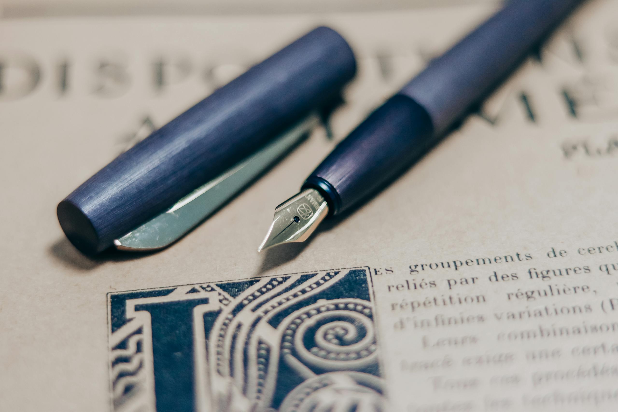 A close-up shot of a navy blue fountain pen on a vintage book page, showcasing elegant writing tools.